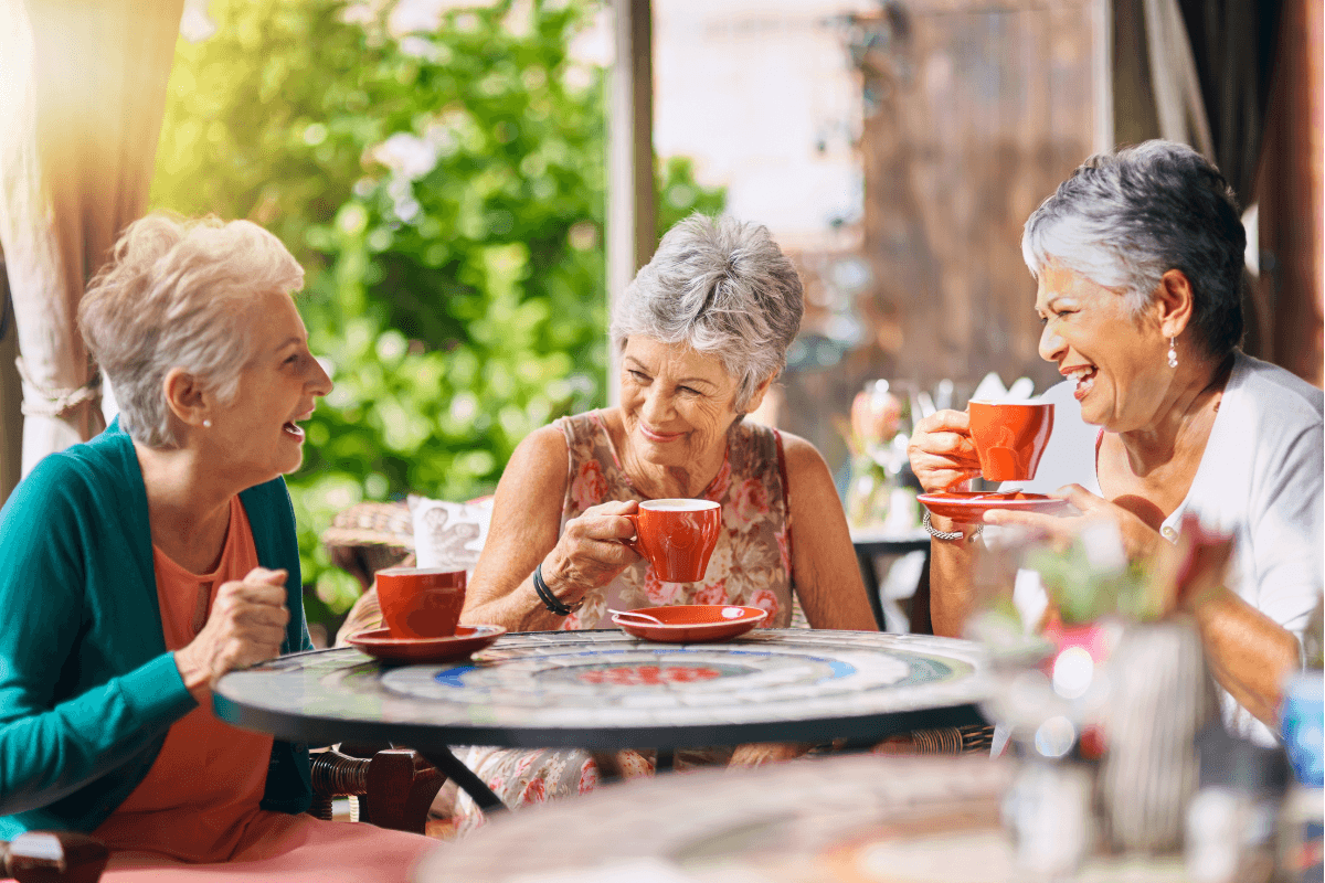 Elderly friends share warm conversation over tea at a cozy restaurant, enjoying a well-deserved afternoon out.